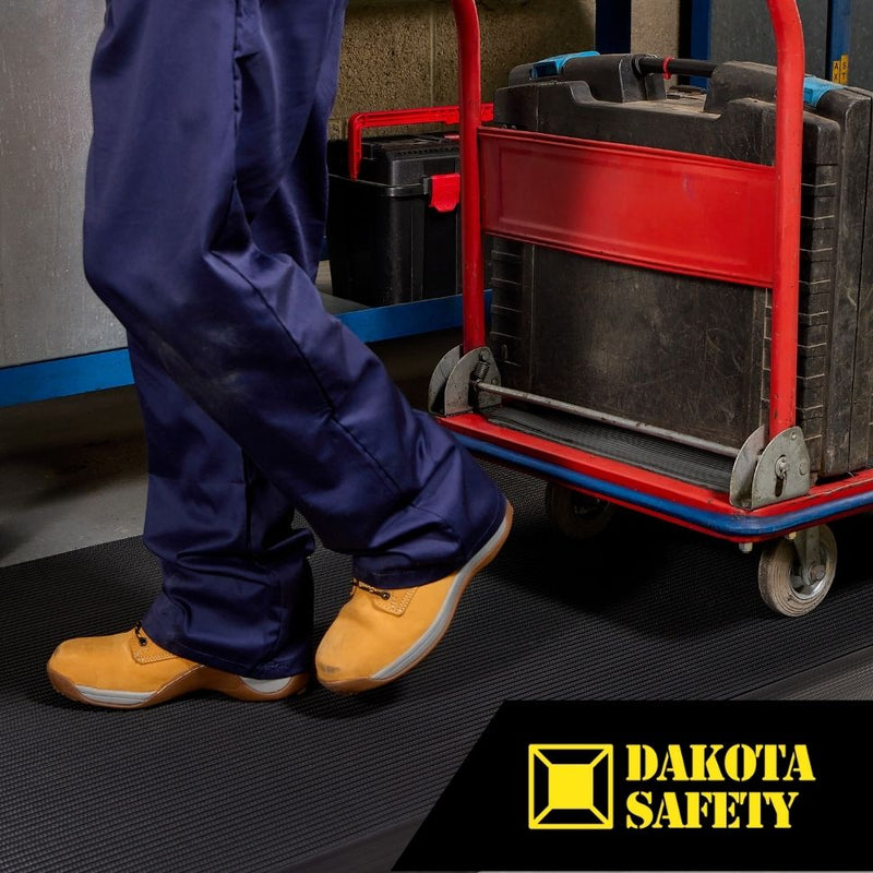Worker in safety boots using Firmagrip anti-slip matting with wheeled cart, showing industrial workplace application