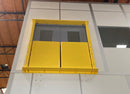 Self-closing mezzanine door gate closed inside an open double hollow-metal door on an upper floor.